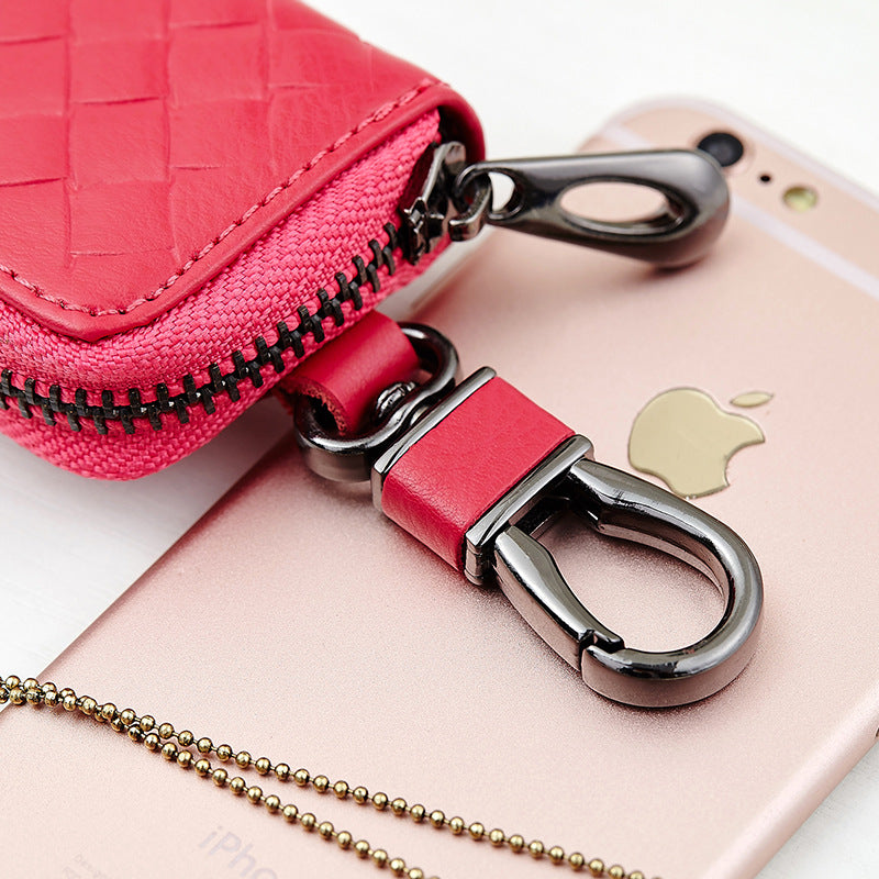 Woven leather car key holder – close-up of pink clasp hook beside a phone